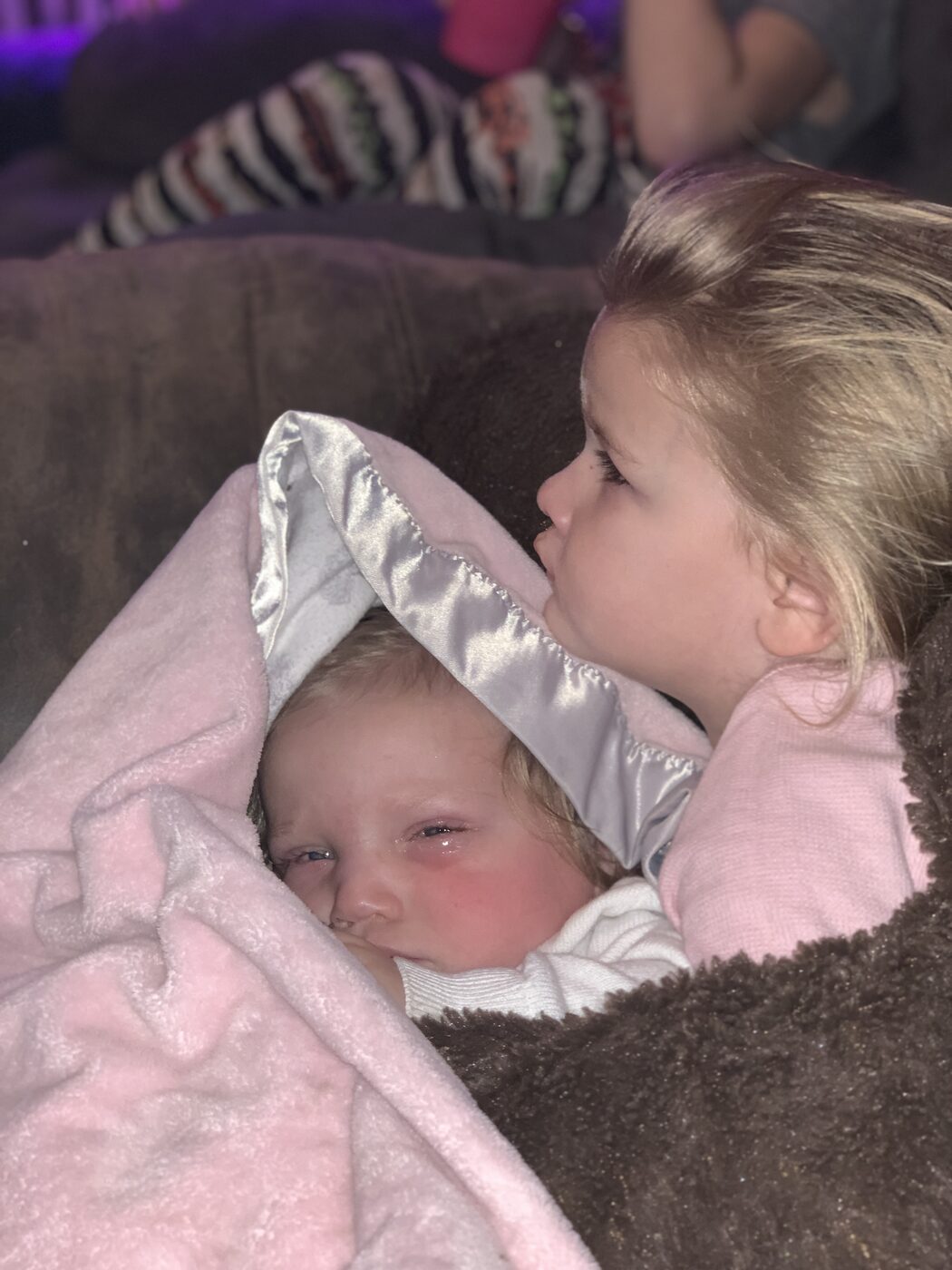 A newborn and big sister wrapped in a Marmee's blanket