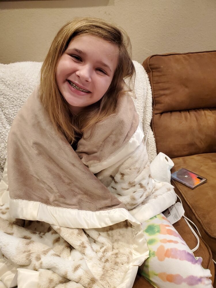 A child wrapped happily in a plush handmade blanket